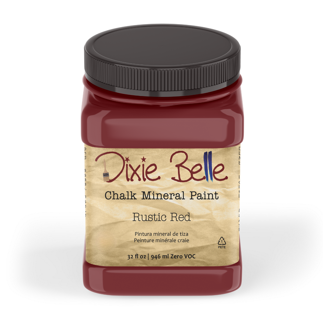 A jar of Dixie Belle Chalk Mineral Paint in the Rustic Red color, featuring a black lid and a beige label, set against a plain white background.