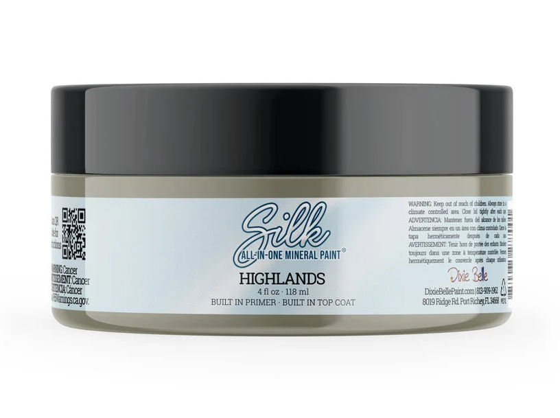 A jar of Silk All In One Mineral Paint in the 'HIGHLANDS' shade, featuring a black lid and a white label with blue and gray text, set against a plain white background.