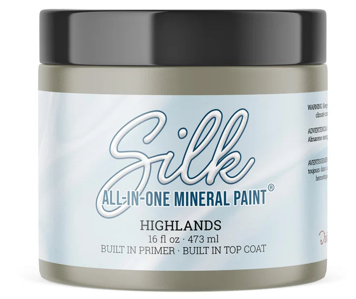 A jar of Silk All-In-One Mineral Paint in the color 'Highlands', featuring a light blue-gray label and a black lid, shown on a white background.