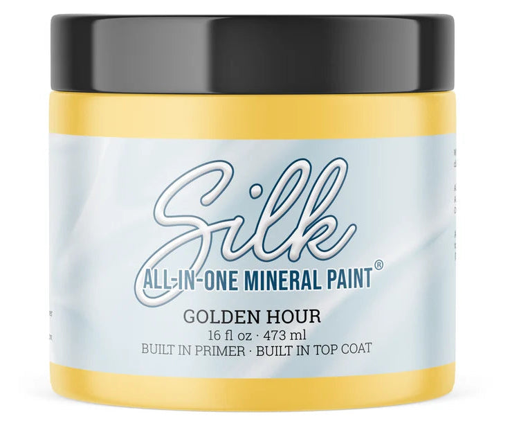 A jar of Silk All-In-One Mineral Paint in the Golden Hour Yellow colour, featuring a light blue and white label with a black lid, set against a plain white background.