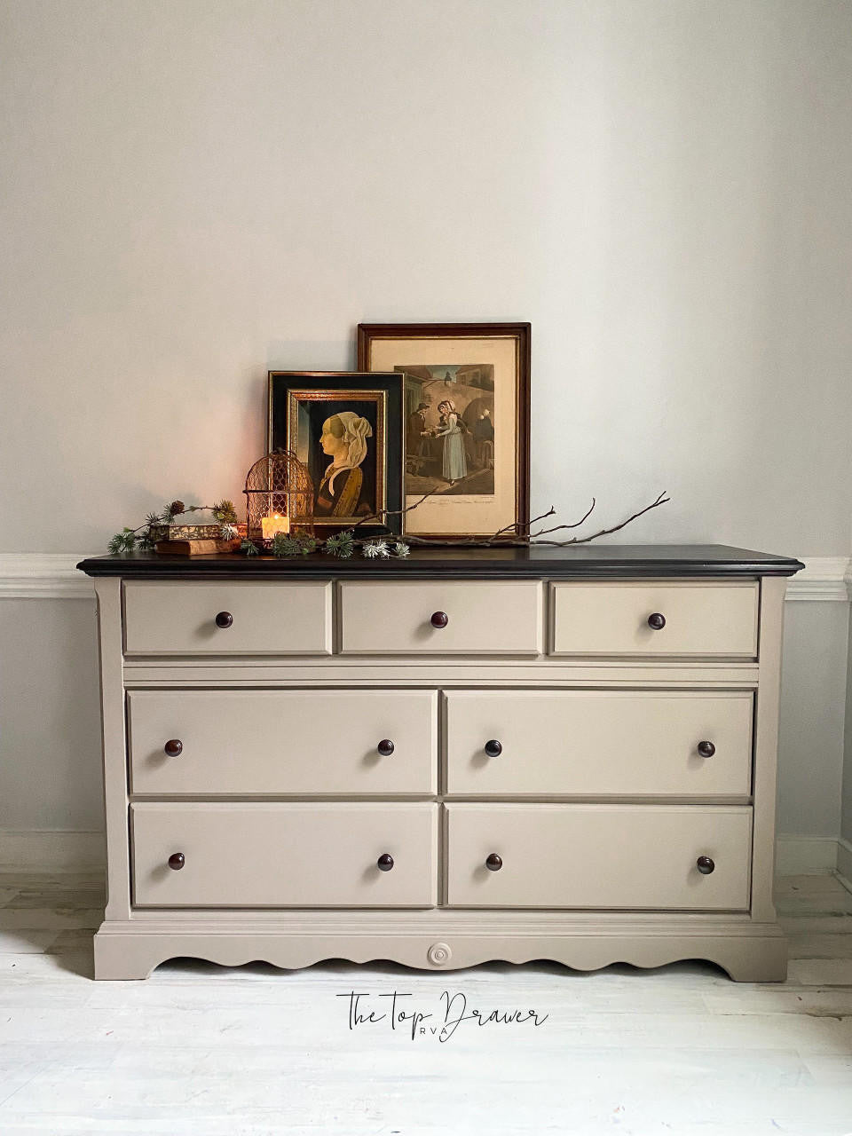 Gray dresser with black top against a white wall, featuring decorative items on top.