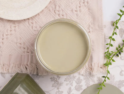 An open round glass jar filled with a pale creamy olive green dixie belle paint