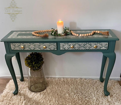 Decorative console table with a candle and decorative items on a white wall background